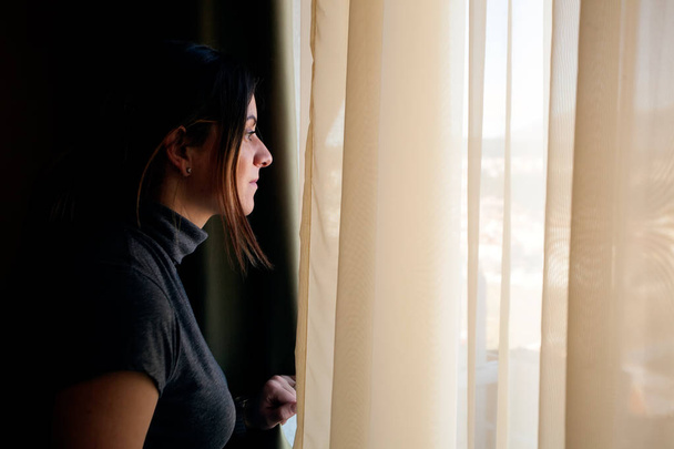 Mujer joven abriendo cortinas en casa
 - Foto, Imagen