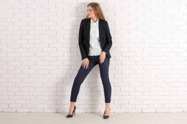Beautiful fashionable woman in elegant suit against white brick wall - Foto, immagini