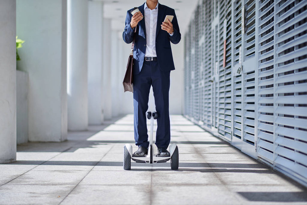 Przycięty obraz business executive jadąc do pracy na gyroscooter - Zdjęcie, obraz