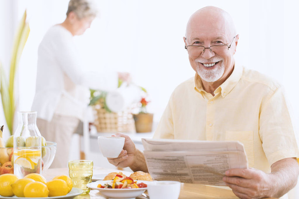 Smiling senior man reading newspaper - Fotó, kép