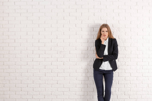 Beautiful fashionable woman in elegant suit against white brick wall - Foto, Imagem