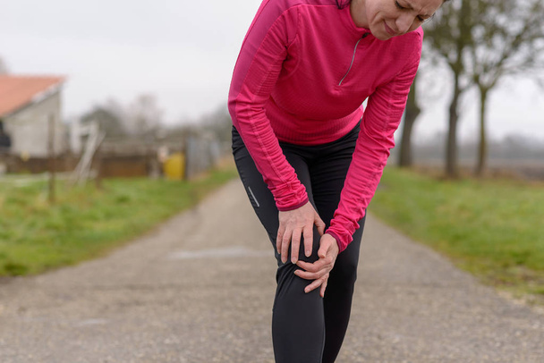 Mujer jogger agarrando su rodilla lesionada
 - Foto, imagen
