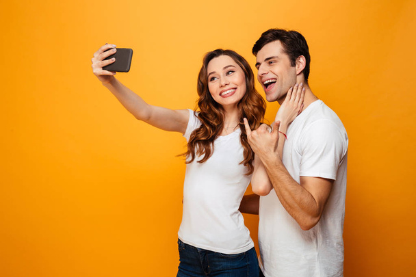 Happy young lovely couple posing together while making selfie - Photo, Image