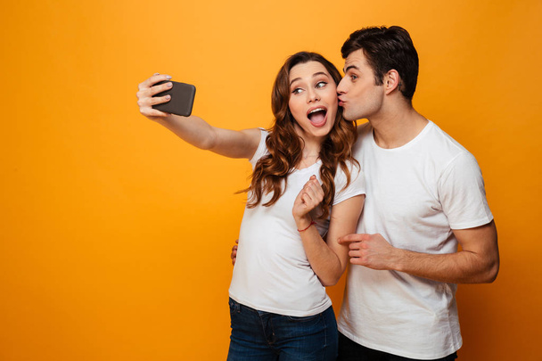 Young lovely couple posing together while making selfie on smartphone - Foto, afbeelding