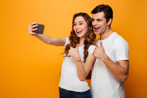 Happy young lovely couple having fun together while making selfie - Photo, Image