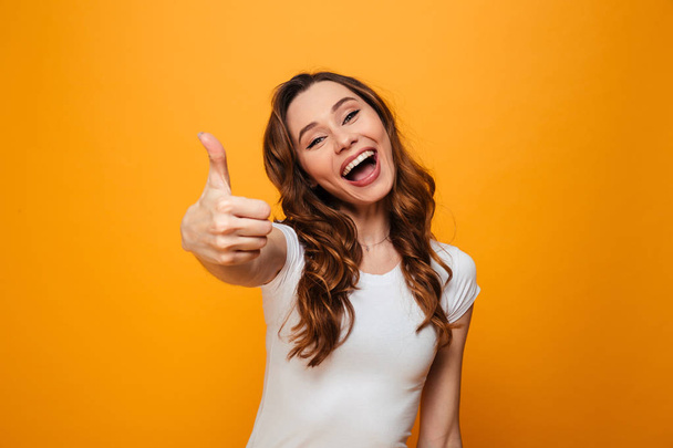 Cheerful brunette woman in t-shirt showing thumb up - Фото, зображення
