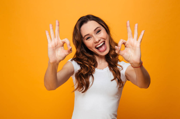 Happy brunette woman in t-shirt showing ok signs - Photo, image