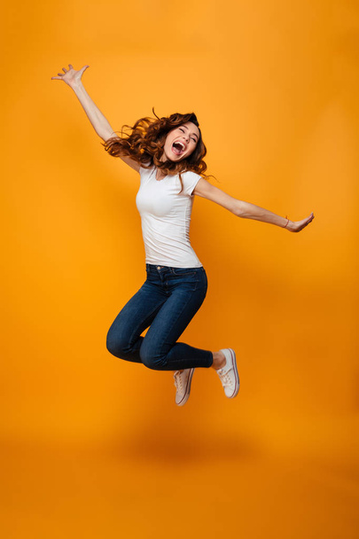 Full length image of Cheerful brunette woman in t-shirt jumping - Foto, Imagen