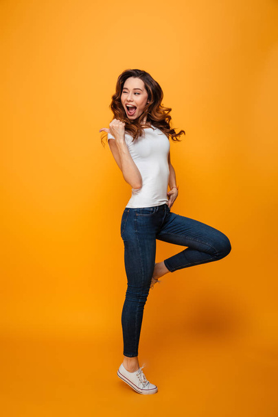 Full length image of Joyful brunette woman in t-shirt jumping - Фото, зображення