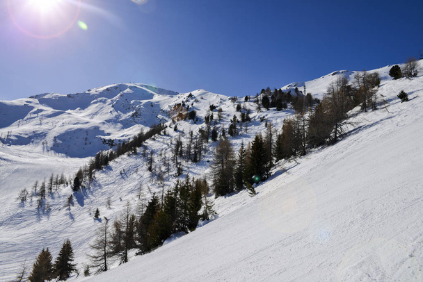 Steile Steilpiste in den italienischen Alpen, vor einem wunderschönen blauen Himmel und Sonnenstrahlen - Foto, Bild