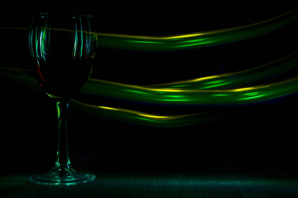A glass of red wine in night club. The light effect. - Photo, image