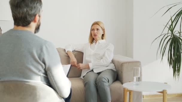 Adult stressed woman with depression talking with male professional psychoanalyst in psychotherapy office indoors - Imágenes, Vídeo