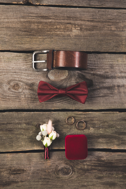 flat lay with arranged grooms accessories and wedding rings on wooden tabletop - Fotó, kép