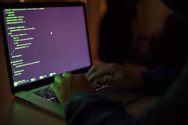 Cybercrime, ein Laptop-Hacker, schreibt Codes, um unbefugten Zugriff zu erhalten - Foto, Bild