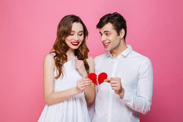 Happy loving couple holding two halves of heart. - Fotografie, Obrázek