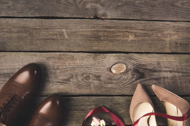 flat lay with ribbon, corsage, bridal and grooms shoes on wooden tabletop - Zdjęcie, obraz