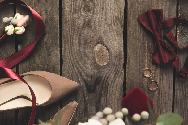 pose plate avec chaussures de mariée, noeud papillon, alliances sur surface en bois
 - Photo, image
