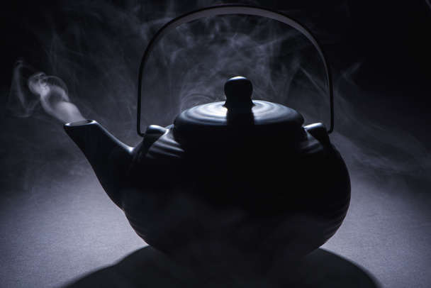 close-up view of black chinese teeapot with hot steam on black
  - Фото, изображение