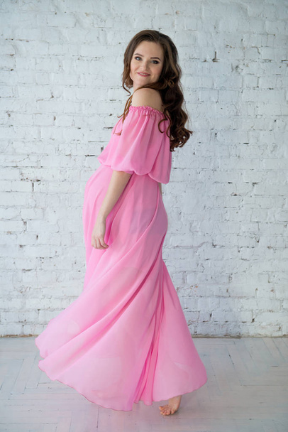 Beautiful tender pregnant woman in pink dress - Foto, afbeelding