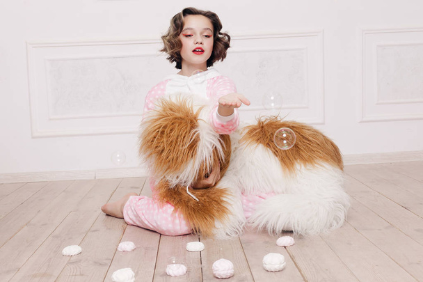 Cute little girl in pajama with sweets sitting on the floor - Foto, Imagen