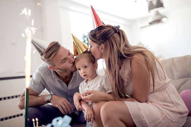 Γιορτή, οικογένεια, διακοπές και γενέθλια έννοια-ευτυχής οικογένεια με παιδί καπέλα και κέικ στο σπίτι - Φωτογραφία, εικόνα