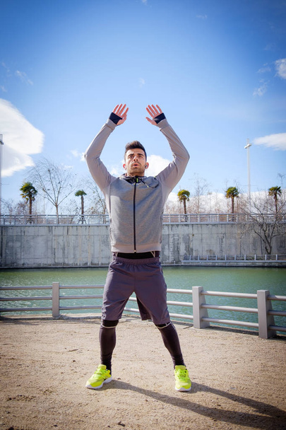 Jovem atleta homem aquecendo antes de correr em um parque
 - Foto, Imagem