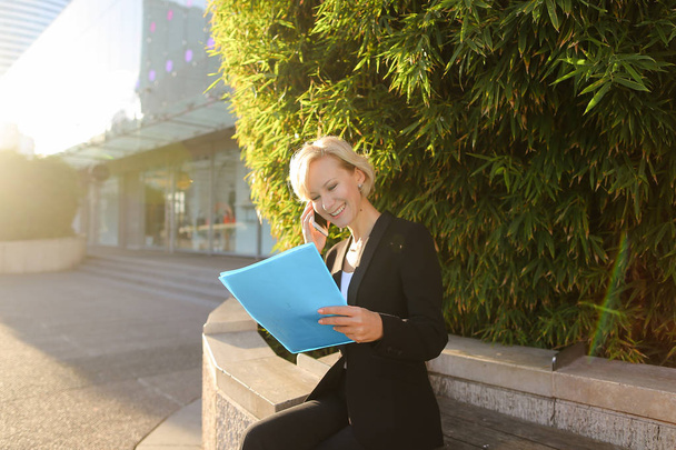 Businesswoman speaking by smartphone outside with document case. - Photo, Image