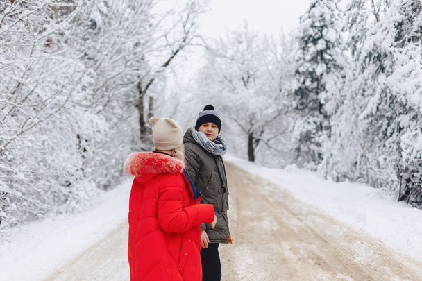 A beautiful family couple walking on a snowy road in the woods - Foto, Imagen