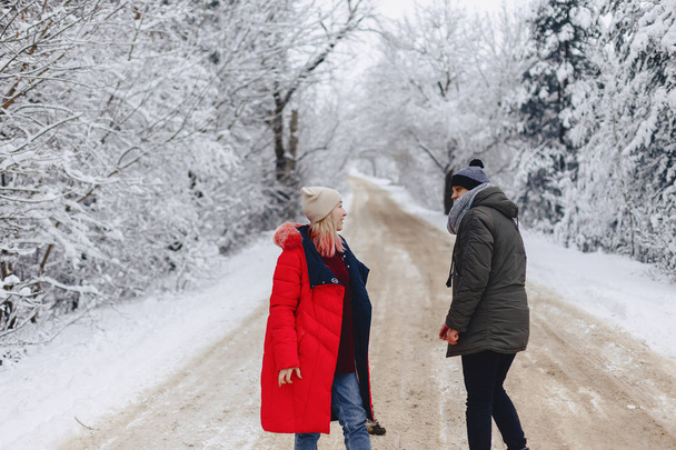 A beautiful family couple walking on a snowy road in the woods - Photo, Image