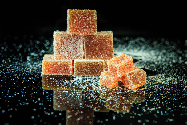 pyramid of delicious orange marmalades coated with sugar on black mirror background - Foto, Imagem