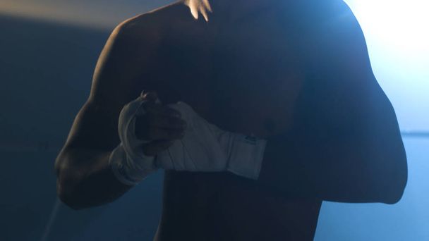 Homme fléchissant les poings avant une bagarre. Gros plan d'un jeune boxeur thaïlandais mains cordes de chanvre sont enveloppés avant le combat ou l'entraînement
 - Photo, image