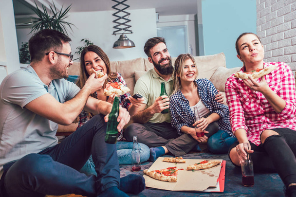 Група молодих друзів їдять піцу на домашній вечірці
. - Фото, зображення