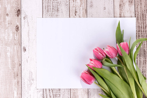 Roze tulpen op houten achtergrond met een lege witte kaart - Foto, afbeelding