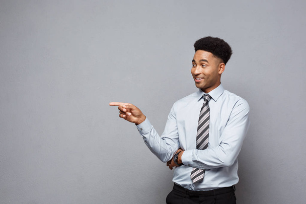 Businessconcept - vertrouwen doordachte jonge African American wijzende vinger aan kant over grijze achtergrond. - Foto, afbeelding