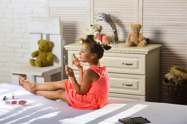 Criança com acessórios de maquiagem usa vestido elegante dentro de casa
 - Foto, Imagem