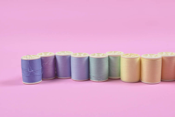 Flat lay of colored thread rolls for sewing on pink background,  - Φωτογραφία, εικόνα
