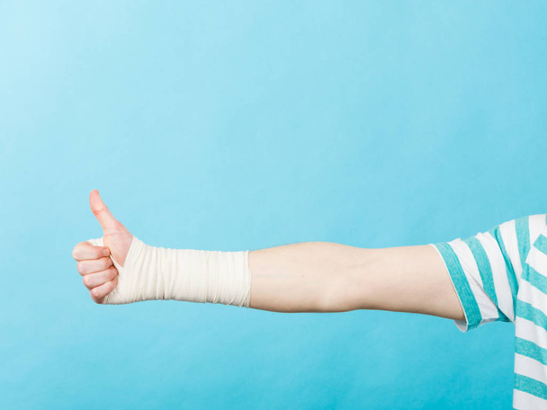 Man with bandaged hand showing thumb up. - Fotografie, Obrázek