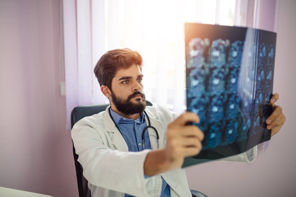 Un joven médico analiza la imagen de rayos X en el hospital
. - Foto, Imagen