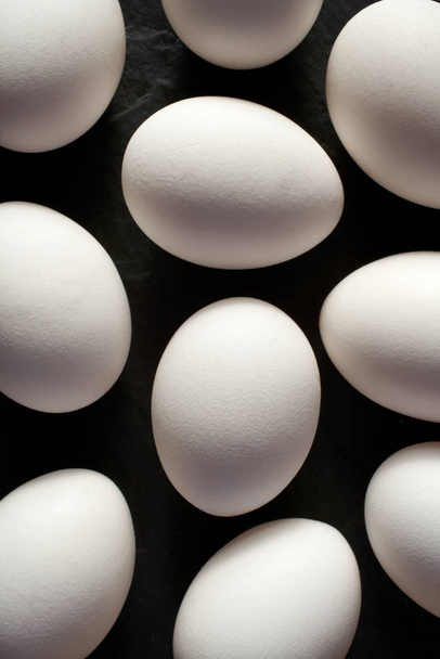       Chicken eggs with white shells on a black background, top view, close-up                          - Fotó, kép