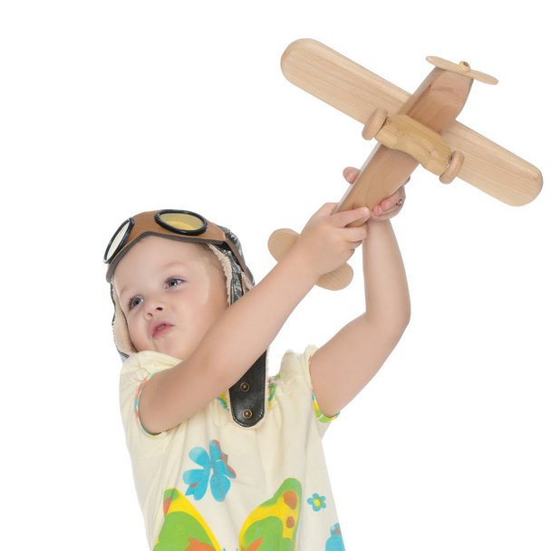 Маленькая девочка с деревянным самолетом в руке. - Фото, изображение