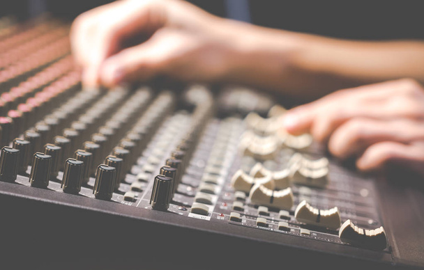 male sound engineer hands working on audio mixing console - 写真・画像