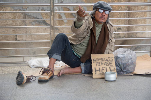Hombre adulto mayor sin hogar sentado y mendigando en el paso elevado
 - Foto, Imagen