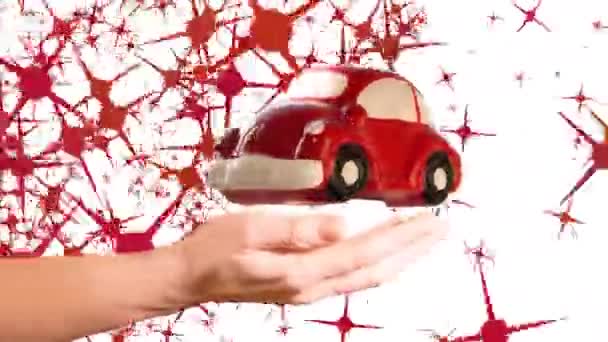 Modelo rojo del coche del juguete que da vuelta sobre la mano de la mujer en un fondo blanco con la animación de la forma de las estrellas
. - Imágenes, Vídeo