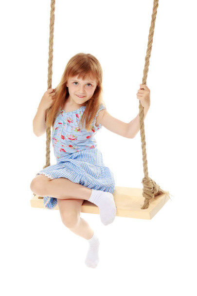 Little girl swinging on a swing - Фото, изображение