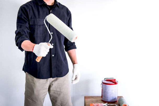 Pintor masculino con brazo cruzado sosteniendo rodillo de pintura, varita interior
 - Foto, imagen