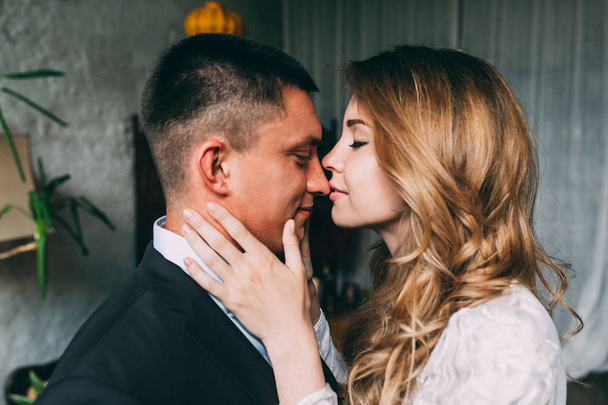 Bride and groom. The bride kisses the beloved in the nose holding his neck. The girl kisses the guy in the nose. The arms of the bride and groom. - Фото, зображення