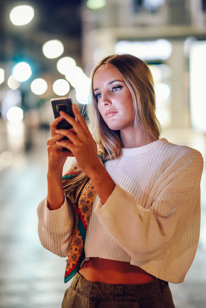 Γυναίκα λήψη φωτογραφίας με smartphone το βράδυ στο δρόμο - Φωτογραφία, εικόνα