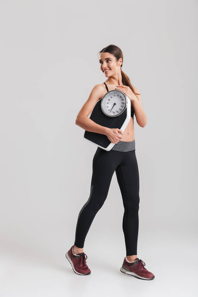 Full-length image of fitness sporty girl holding scale and smili - Fotoğraf, Görsel