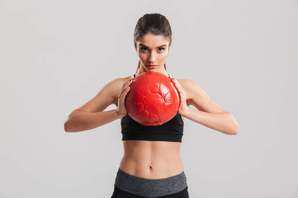 Photo of focused sportswoman doing exercises while holding fitne - Photo, Image