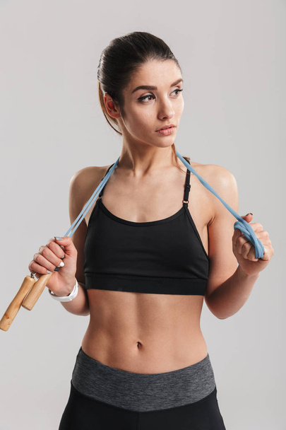Portrait of sporty woman looking aside and holding jumping rope  - Photo, image